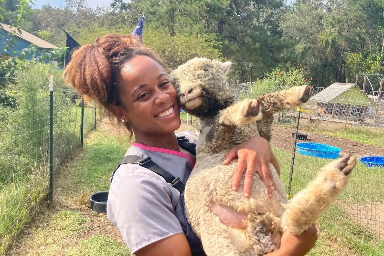 Dr. Sarah Blackwell smiling while holding an alpaca on a farm
